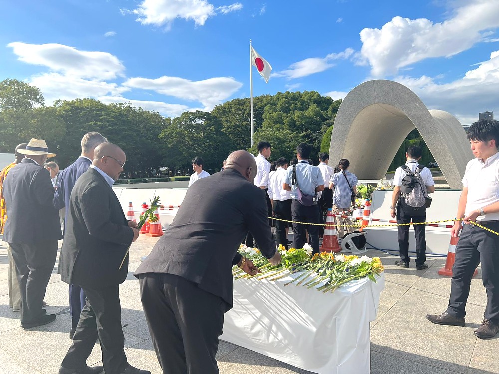 Balozi Baraka Luvanda akiweka maua mbele ya kaburi walimozikwa waathirika wengi wa mlipuko wa Nyuklia tarehe 06/08/1945.