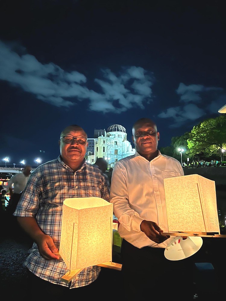 Balozi Baraka Luvanda aliyeambatana na Afisa Ubalozi Bw. Hosea Chikolongo wakiwasha mishumaa pembeni mwa mto ambamo miili ya watu wengi ilionekana ikielea baada ya mlipuko.